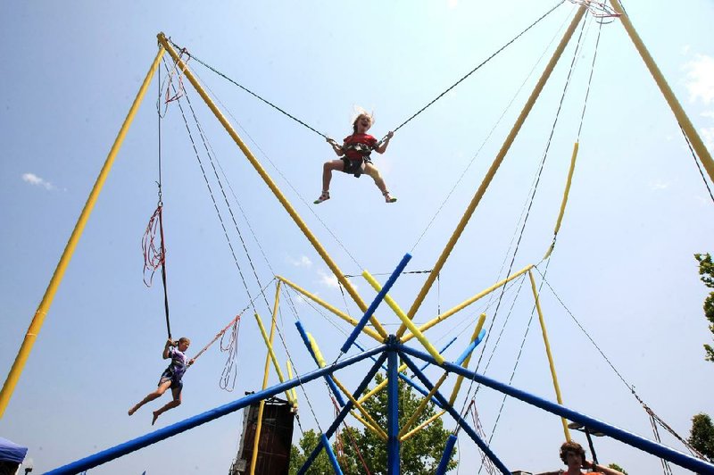 Catherine Justice (center), 6, of Little Rock and Katlynn McCoy, 11, of Brinkley jump on the Quad Power jump attraction Sunday afternoon at Riverfest in downtown Little Rock. 