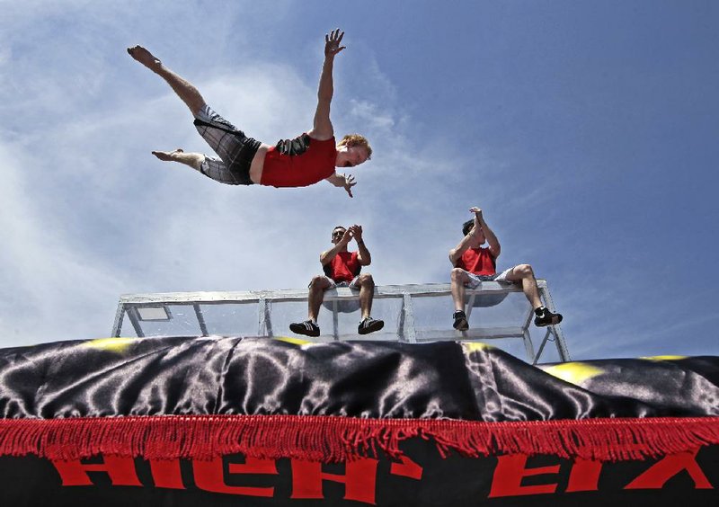 Nick Johnson (foreground) performs stunts Saturday along with other members of the Flippenout Extreme trampoline team at Riverfest in Little Rock. 