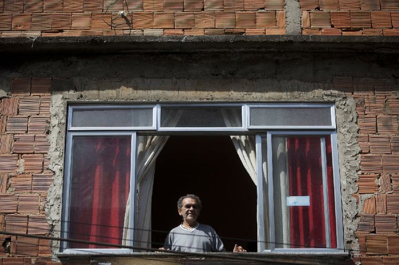 Jose Nazare Braga looks out the window of his home in the Rocinha shantytown in Rio de Janeiro. For decades, the property wasn’t his, and he lived in fear that he would lose it. 