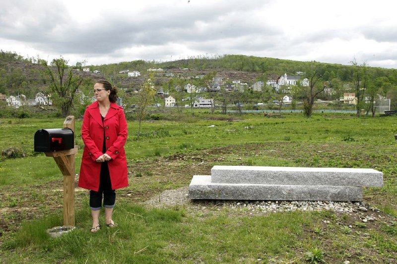 Pia Rogers stands next to her front steps May 10 in Monson, Mass., the only part of her house left a year after a tornado blew through central Massachusetts. 