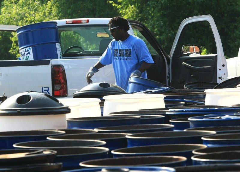 Mason Richardson of the Little Rock Parks Department unloads trash barrels Monday morning while cleaning up after Riverfest. 