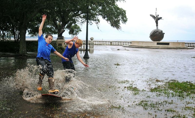 Connor Sidman (right) and his friend Sean Frechette skim boards around Memorial Park in Riverside, Fla., in the aftermath of Tropical Storm Beryl on Monday. 