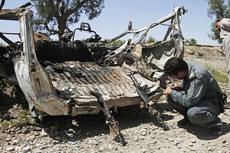 An Afghan policeman checks a vehicle driven by two suicide bombers that exploded prematurely Tuesday on the main highway between Jalalabad and Torkham on the Pakistani border. 