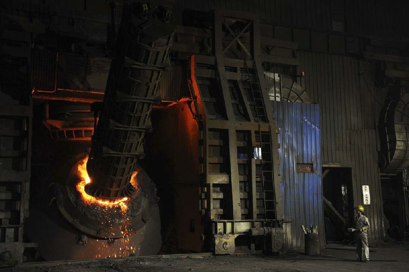 A worker stands near molten steel at a steel plant in Hangzhou in eastern China’s Zhejiang province on Wednesday. Chinese officials said Tuesday that the government is not planning another huge stimulus plan for the slowing economy. 