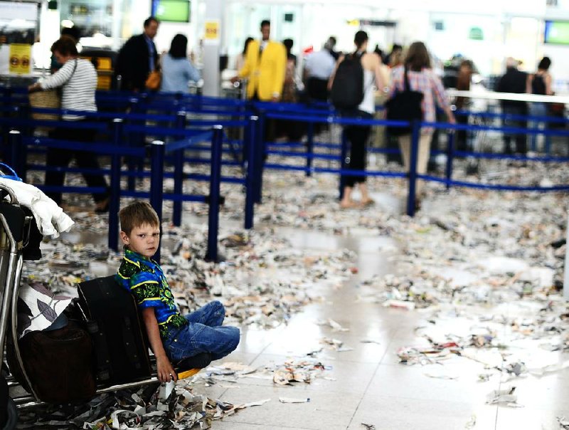 A child sits in Barcelona’s international airport Wednesday, where the cleaning staff in the second day of a strike left torn paper on the floor in protest of budget cuts. Spain’s borrowing costs Wednesday came close to levels that forced Greece and Ireland to ask for international bailouts. 