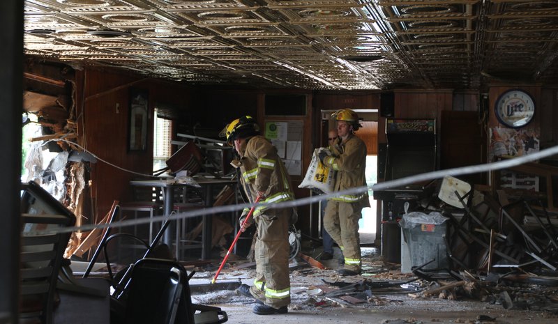 Little Canada Firemen sweep up after wrecker crews pulled a pick-up truck out of the side of Gordies Bar after it crashed through the wall sending four people to the hospital Wednesday, May 30, 2012 in Little Canada, Minn.