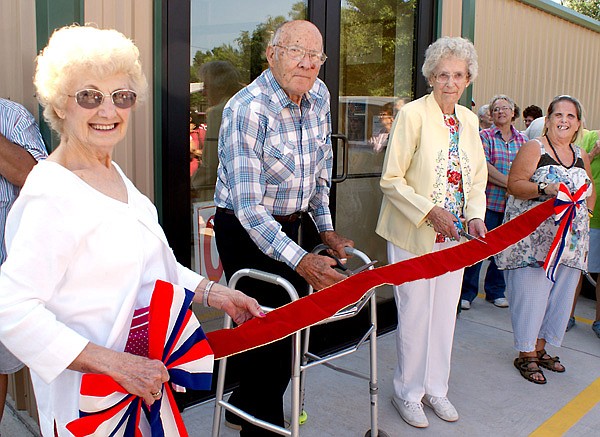 Marion Roberts and Virginia Todd, center, prepare to cut the ribbon at the opening of the new Care and Share store as Betty Howard, left, and Vickie Hearne hold the bright red ribbons.