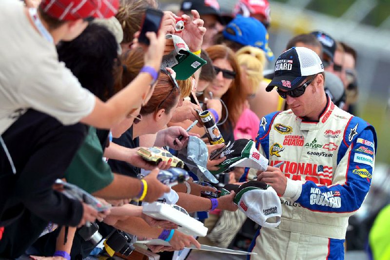 Dale Earnhardt Jr. signs autographs during qualifying for the NASCAR Sprint Cup Series auto race at Pocono Raceway, Saturday, June 9, 2012, in Long Pond, Pa. (AP Photo/Autostock, Brian Czobat) MANDATORY CREDIT