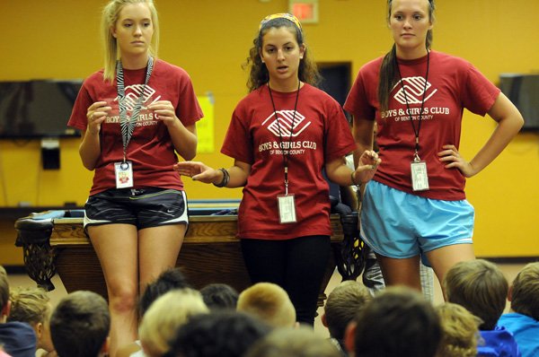 Brittany Lockridge, left, Aine McMahon and Baylee Burgess give instructions to a group of children Tuesday in the gameroom at the Boys & Girls Club of Benton County’s McKinney Unit in Bentonville. Lockridge, McMahon and Burgess are all recent high school graduates working through the summer before attending college in the fall. 