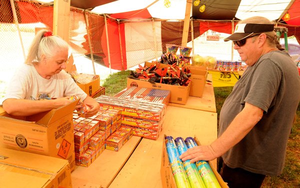 Susan Mathews and husband, Larry, stock the Rainbow Fireworks stand Saturday getting ready for its Wednesday opening in Bethel Heights.