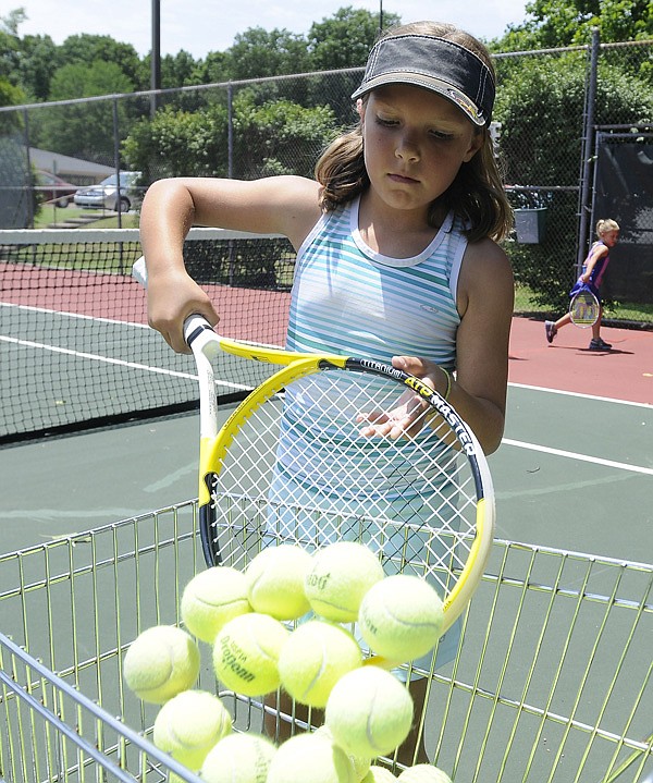 Paige Weston, 8, of Bentonville picks up tennis balls Thursday during the Cancer Challenge’s junior tennis clinic in Bella Vista. Officials hoped to raise $2,500 with the clinic and junior tournament. 