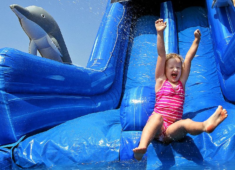 Arkansas Democrat-Gazette/BENJAMIN KRAIN --6/22/12--
Lilly Duellman slides down a large inflatable waterslide while playing with classmates at Kid's Academy in Maumelle. Every Friday students at the day care center get to play in the water and eat snowcones.