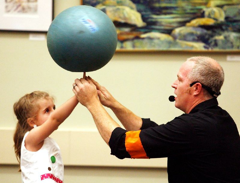 Arkansas Democrat-Gazette/JASON IVESTER --06/21/12--
Galen Harp (right) helps Sophie Calvi (cq), 5, of Bentonville spin a ball on her finger inside the Bentonville Public Library on Thursday, June 21, 2012. Harp and his partner, Ella Winters, both with the Institute of Jugglology, put on a demonstration for children at the library.