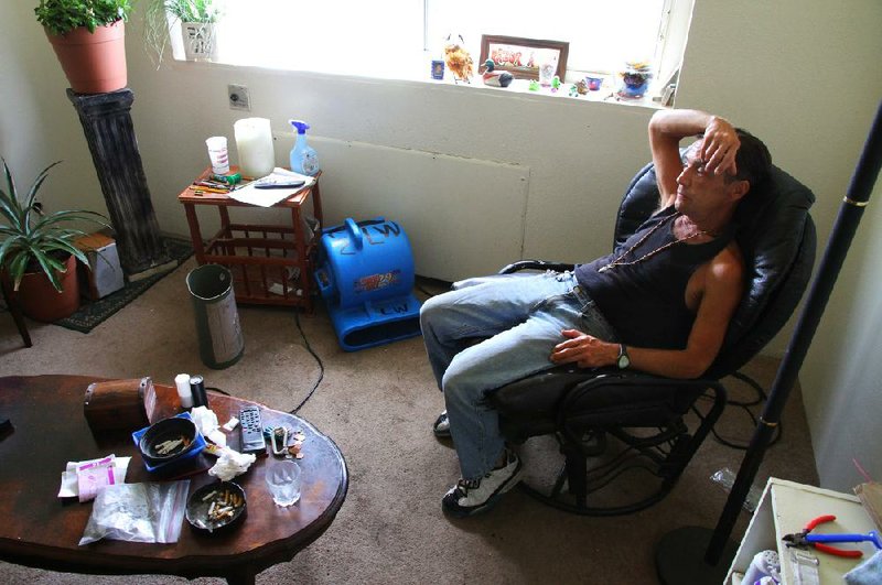 Patrick Keck sits in his apartment Thursday on the ninth floor of Plaza Towers in Little Rock as a blower works to dry the wet carpet. Keck said he awoke Wednesday night to find 3 inches of hot water on the floor. 