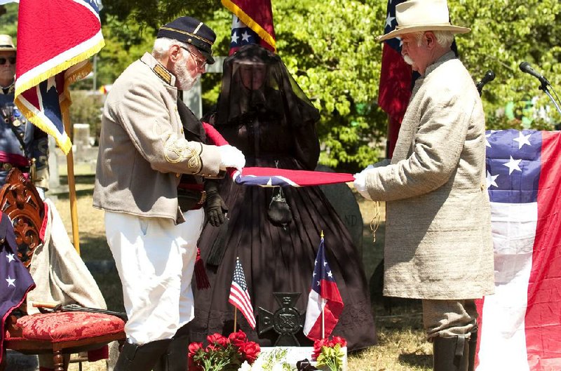 Ray Jones (left) folds a Confederate battle flag with the help of Jack Stevens during a monument dedication and memorial service that marked the graves of 18 Confederate soldiers and one Union soldier Sunday afternoon at Mount Holly Cemetery in Little Rock. 