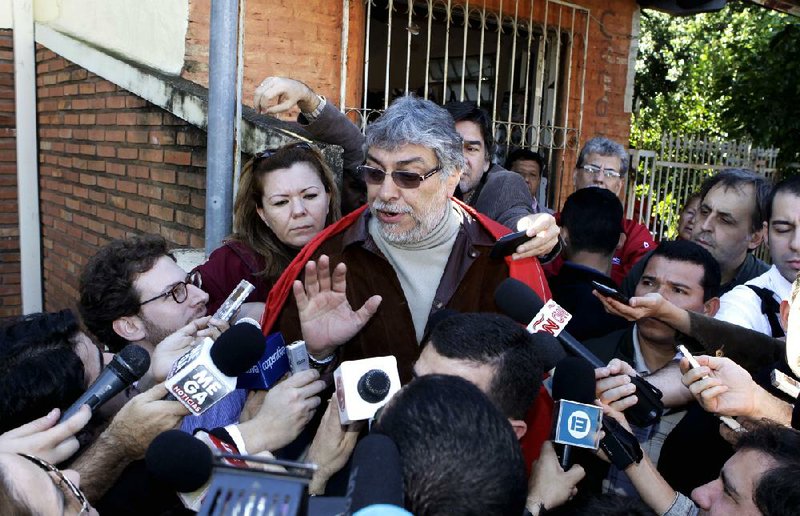 Former President Fernando Lugo (center) talks to reporters outside his home Sunday in Lambare, Paraguay. 