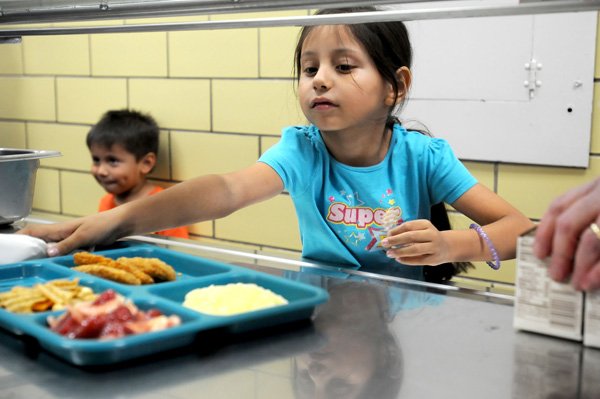 Andrea Villafranca, 7, gets her lunch tray during the summer school lunch program Wednesday at Jones Elementary School in Springdale. Andrea, along with her brother and mother, have been coming to the summer lunches since right before she started kindergarten. The daily number of lunches served begins to decline in midsummer.