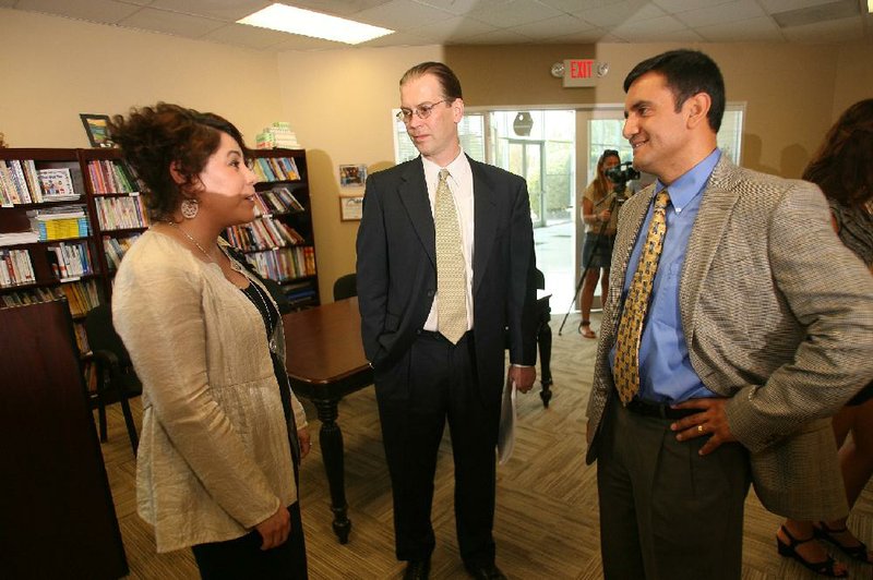 Arkansas United Community Coalition Executive Director Mireya Reith (from left) Charles M. Kester and Geovanny Sarmiento of the Rogers/Lowell Chamber of Commerce talk Monday after a news conference at the Family Resource Center in Springdale.