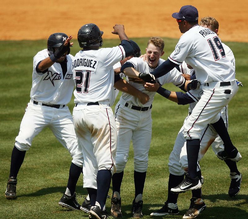 Northwest Arkansas shortstop Alex McClure (center), playing in only his sixth game in Class AA, celebrates with teammates Yem Prades (19) and Julio Rodriguez (21) after his ninth-inning single with two outs scored Carlo Testa from second with the winning run in a 3-2 victory over the Arkansas Travelers on Monday at Arvest Ballpark in Springdale. 