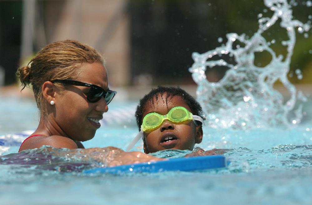 Arkansas Democrat-Gazette/RYAN MCGEENEY --06-25-2012--  Fayetteville Athletic Club swim instructor Karella Balentine [cq], left, works with student Mikayla [cq] Anderson, 7, on basic kicking Monday morning at the center's outdoor pool in Fayetteville. Temperatures throughout the region are predicted to rise above 100 degrees this week.