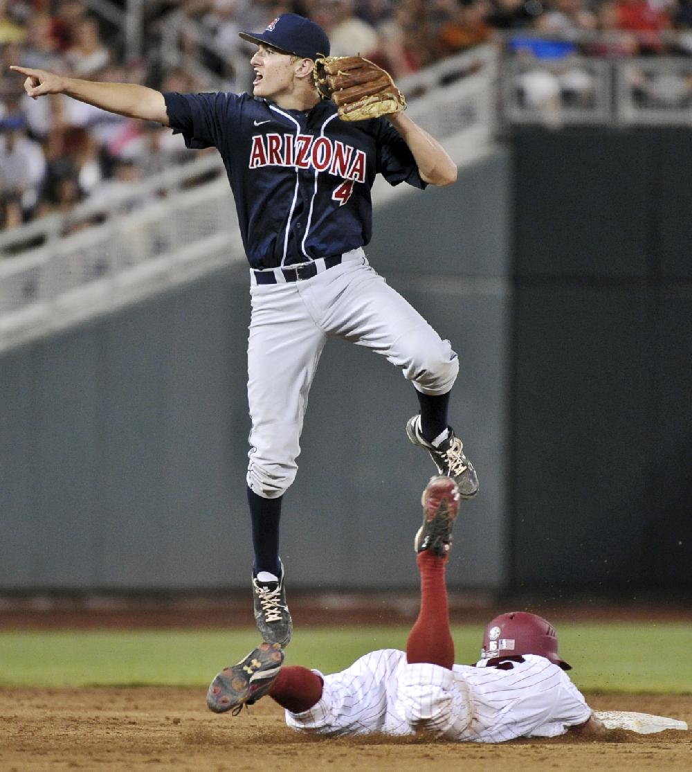 Arizona second baseman Trent Gilbert (4) leaps over South Carolina's Chase Vergason, who stole second base and went on to third on a throwing error, in the eighth inning of Game 2 of the NCAA College World Series baseball finals in Omaha, Neb., Monday, June 25, 2012. (AP Photo/Ted Kirk)