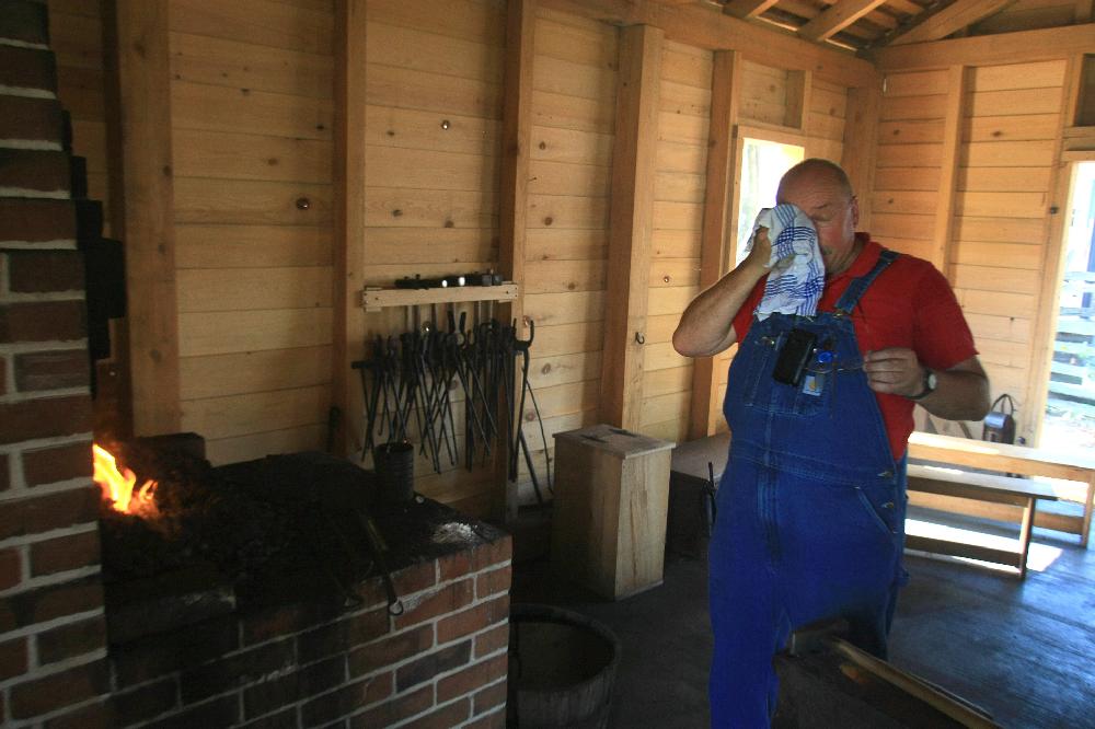 Arkansas Democrat-Gazette/RICK MCFARLAND --06/25/12-- Lin Rhea, a Master Smith, wipes sweat away as he fires the forge in the blacksmith shop at the Historic Arkansas Museum in Little Rock Monday. He was preparing for a demonstration on forging techniques.