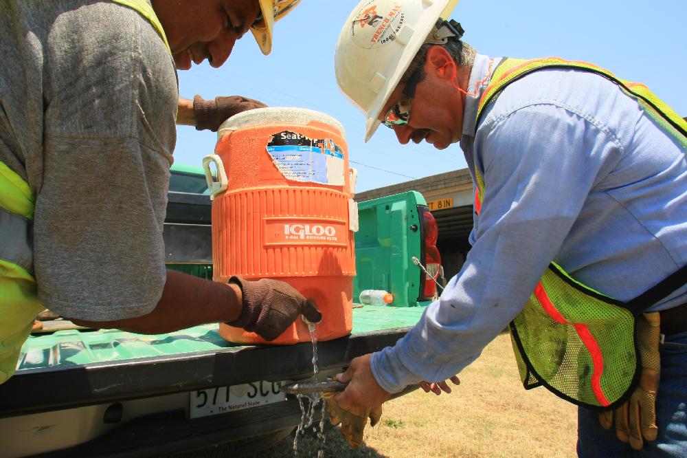 Arkansas Democrat-Gazette/RICK MCFARLAND --06/25/12-- Glenn Mixon (right) and Victor Contreras use cold water to cool off an air hammer chisel they wanted to use that had been lying in the sun and gotten too hot to handle. Temperatures were over 100 degrees when they were working on the drainage at Bishop Lyndsey Ave. and Interstate 30 in the North Little Rock Monday.
