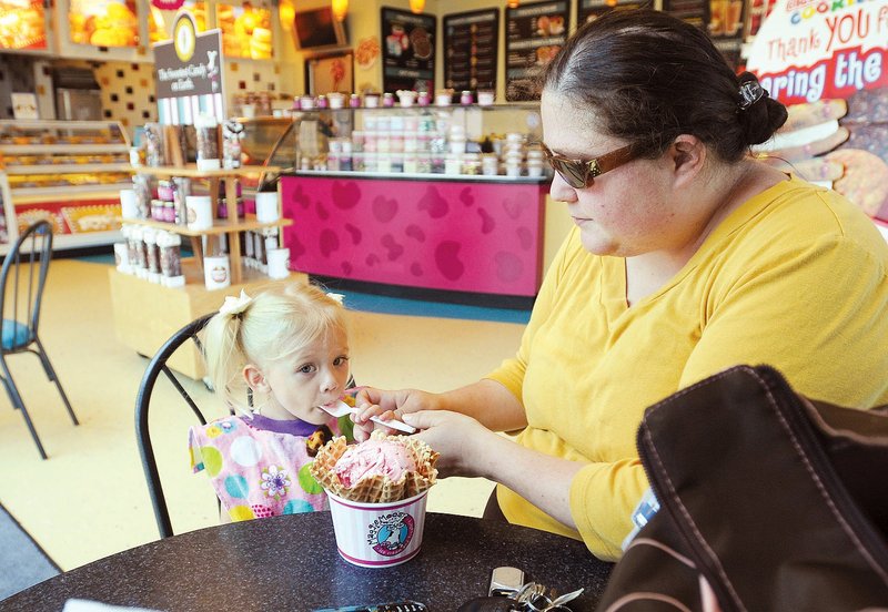 STAFF PHOTO SAMANTHA  BAKER
Cortine Parson, right, helps Cailyn Parson, 2, with her strawberry ice cream Tuesday, June 26, 2012 at Maggie Moo's in Fayetteville. On July 3, the city council will discuss reversing a planning commission decision that allowed a shaved ice mobile vendor to operate longer than 90 days. Tracy Hoskins, whose wife owns Maggie Moo's, contests the extension shouldn't be allowed as it provides and unfair advantage compared to established, non-mobile businesses in the area.