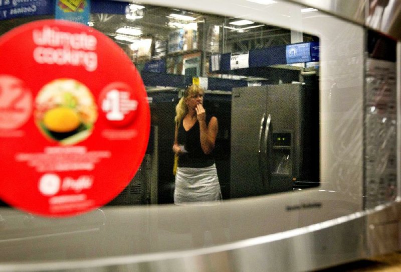 In this June 19, 2012,photo, a shopper is reflected in a microwave oven on display on a showroom floor at Lowe's store in Atlanta.  Consumer confidence fell in June for the fourth month in a row as lingering worries about the economy outweighed relief at the gas pump, according to a private research group. (AP Photo/David Goldman)