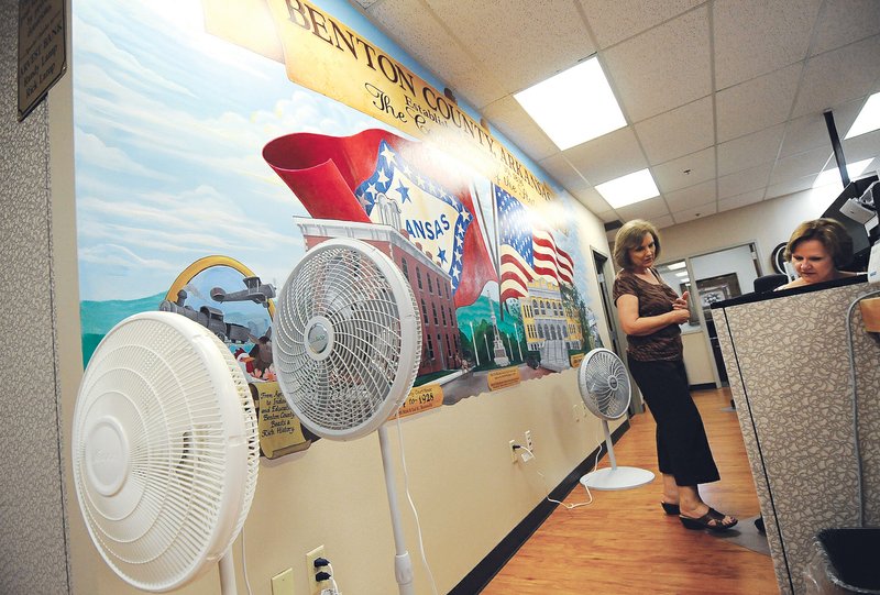 Fans line a wall Wednesday, June 27, 2012, in the County Collector's Office as Doris Bolain, left, and Gwen Edgerton do their work at the Benton County Administration Building in Bentonville. The building's air-conditioning system broke down earlier this week forcing county employees to rely on fans to try and keep cool during the recent heat wave.