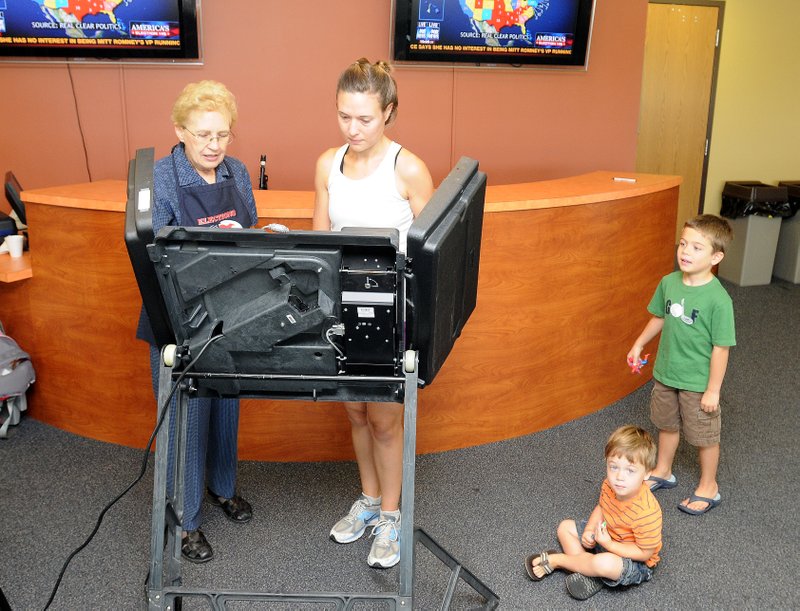 Election volunteer Peggy King, from left, assists Lauren Snodgrass with voting in Tuesday's special millage election while Snodgrass' sons Luke, 2, and Paul, 5, watch at the First Assembly of God Church polling station in Bentonville on Tuesday.