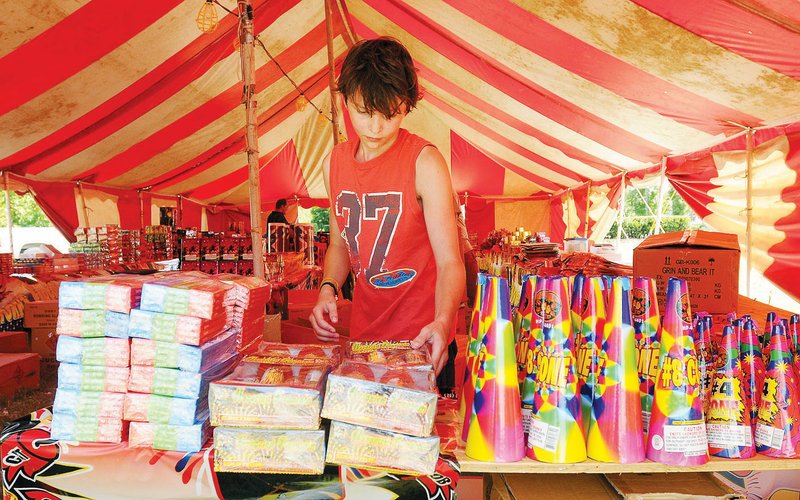 Jonas Kersey, 14, helps to unbox fireworks Wendesday, June 27, 2012 at Phoenix Fireworks located in a tent just north of the intersection of North Crossover Road and East Mission Boulevard in Fayetteville. Many temporary tents selling fireworks will begin selling products today despite a county-wide burn ban.
