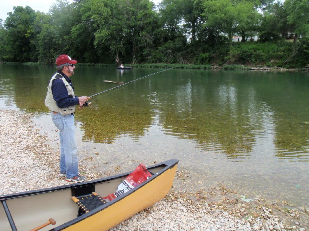 A trash bag of litter that brought good fish karma is in the front of the canoe while Tonkinson fishes at the Shady Beach take-out.