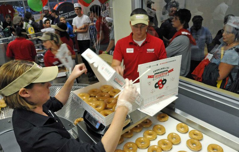 Customers watch as Jordan Evans, left, and Matt Brown package hot doughnuts at the new Indian Land, South Carolina Krispy Kreme that opened for business early morning, June 12, 2012. (Davie Hinshaw/Charlotte Observer/MCT)