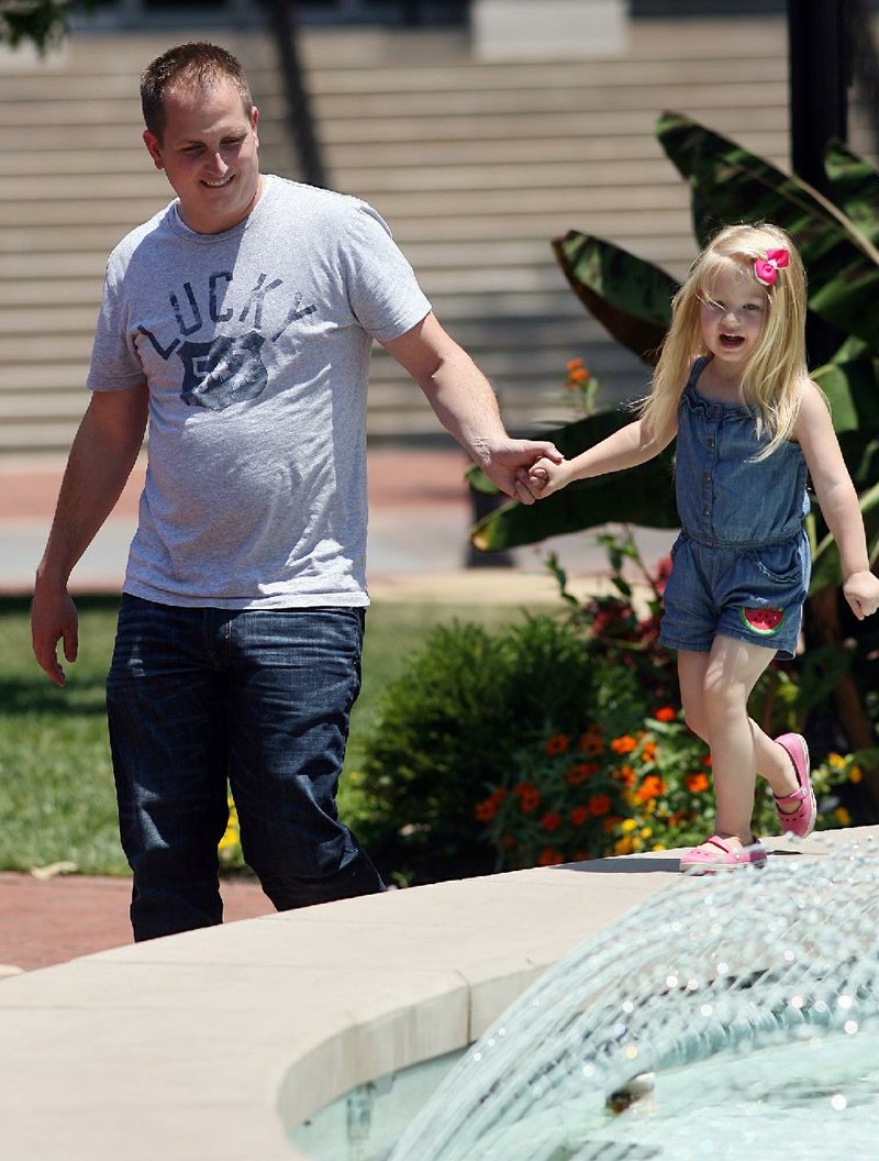 Arkansas Democrat-Gazette/WILLIAM MOORE
Jake Pruett of Centerton holds the hand of his daughter Addison Pruett, 3, Friday, June 29, 2012 as she walks around the rim of the fountain on the square in Bentonville.  Jake was taking his lunch break from with his family on the square.