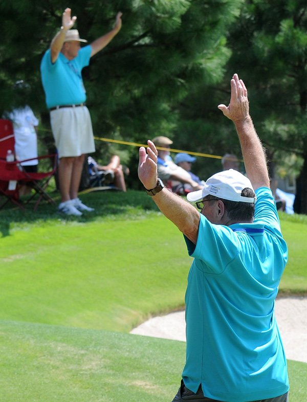 Ron Wozny, right, and Tony Calufetti, volunteers on No. 17 hole, raise their hands for silence Friday at Pinnacle Country Club in Rogers during the first day of regular play for the Walmart NW Arkansas Championship. 