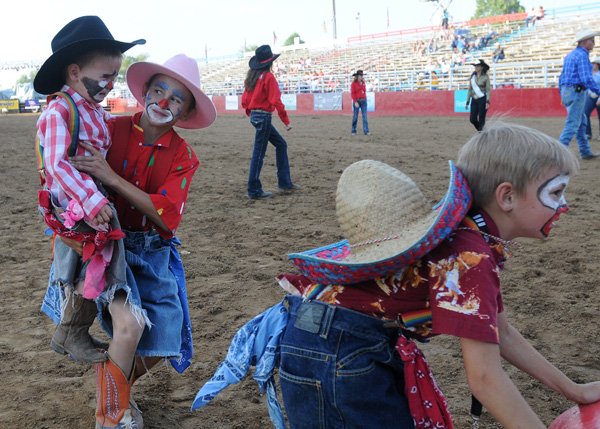 Montgomery Parsons, 8, right, moves a barrel away as Edison Parsons, 3, far left, is comforted by older brother Landon Parsons, 13, Wednesday at Parsons Stadium during the mutton bustin’ competition at Rodeo of the Ozarks. The boys acted as clowns during the event, helping to move competitors out of the arena. 