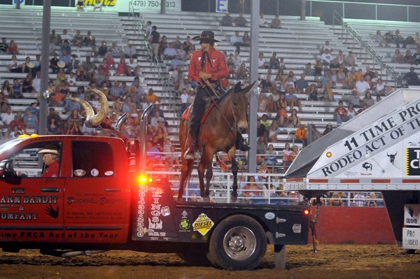 John Payne jumps on the back of a truck Thursday during his show at the Rodeo of the Ozarks at Parsons Stadium in Springdale. Payne lost an arm in an electrical accident but still rides in rodeos across the country. 
