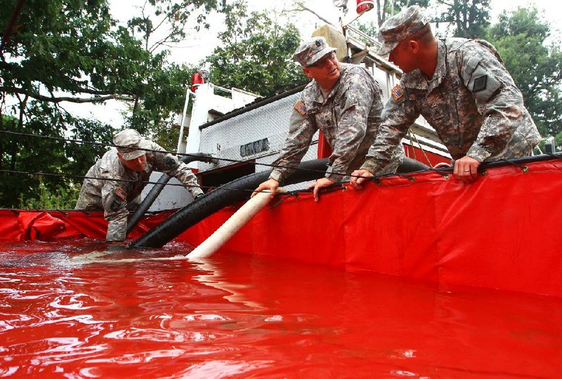 Staff Sgt. Brad Broadstock (from left), Sgt. 1st Class Billy Newbolt and Sgt. Thomas Hesson of the Arkansas National Guard pump water Saturday into a holding tank south of Fallsville in western Newton County. The Guard has been assisting rural water associations in the area during the recent drought. Watch the video at arkansasonline.com/videos. 