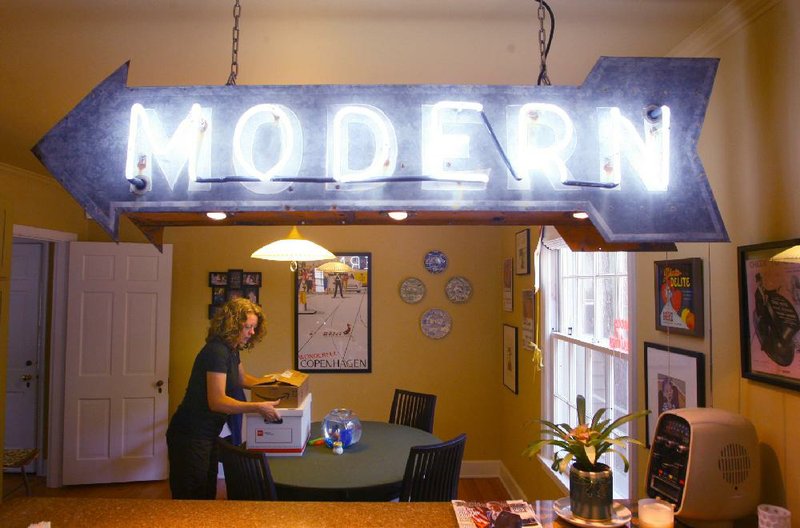 Jill Curran looks through a box of her collection of old motel memorabilia inside her Little Rock home under the “modern” arrow that hangs over the counter, a relic that she salvaged from an old tourist court. 