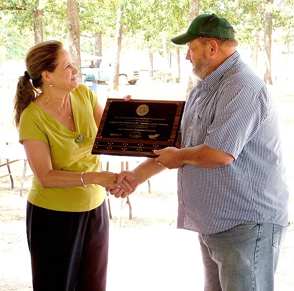 Mary Walter, Occupational Safety and Health Administration Voluntary Protection Programs coordinator, presents a plaque Friday to Terry Smith, manager of the Cargill hatchery in Gentry for being one of 50 company sites in the state to be VPP certified.