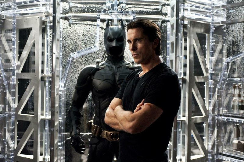 Christian Bale plays Bruce Wayne, standing alongside the suit of his alter ego, Batman. 