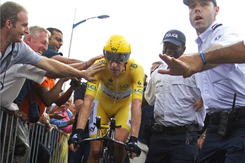 Supporters touch Bradley Wiggins of Britain, who carries the overall lead into today’s final stage of the Tour de France. Wiggins leads Chris Froome of Britain by 3 minutes, 21 seconds. 