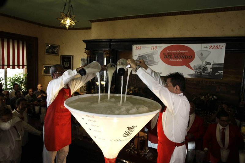 Labrador Ahmed (left) and Eduardo Bautista stand on a platform to pour pitchers of daiquiris into a 71-gallon cocktail glass Saturday in Old Havana, Cuba. 