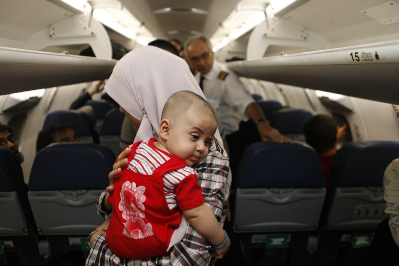 Iraqi refugees board a plane at an airport in Damascus, Syria, on Sunday. Iraq flew hundreds of its citizens out of Damascus to escape the civil war in Syria. 