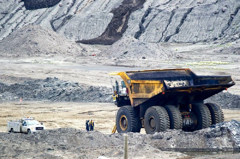 Workers talk near a mining truck at Syncrude Canada Ltd.’s oil sands North Mine in Alberta, Canada, in 2010. The Syncrude mine is a joint venture that includes Nexen Inc., a Canadian oil producer targeted for acquisition by Chinese offshore oil and gas company CNOOC Ltd. 