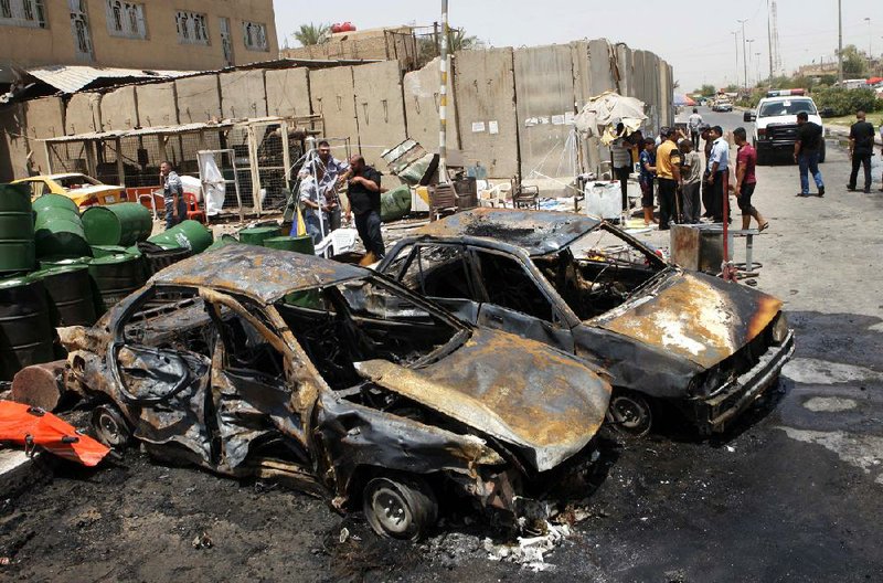The aftermath of a car-bomb attack draws onlookers Monday in Baghdad’s Shiite enclave of Sadr City. Insurgents launched at least 40 attacks throughout the country. 