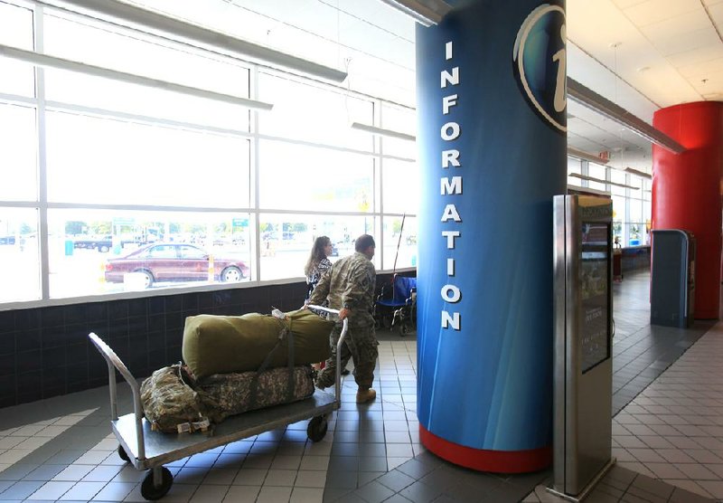 Passengers walk past one of the new digital service centers Tuesday at Bill and Hillary Clinton National Airport/Adams Field. The new interactive LCD screens allow passengers to get information on local businesses and activities. 