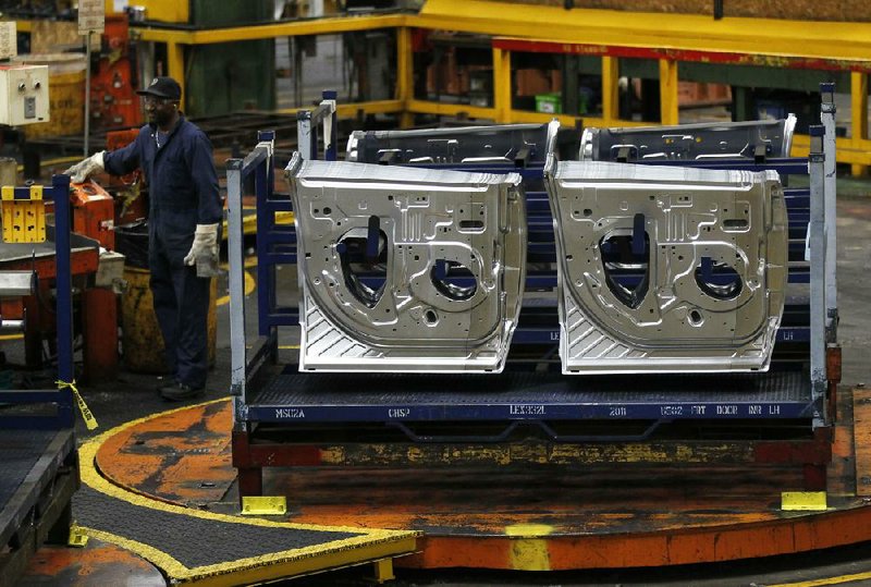 An autoworker operates a machine in April at the Ford Stamping Plant in Chicago Heights, Ill. Slow sales in Europe led Ford Motor Co. to lower its full-year earnings forecast. 