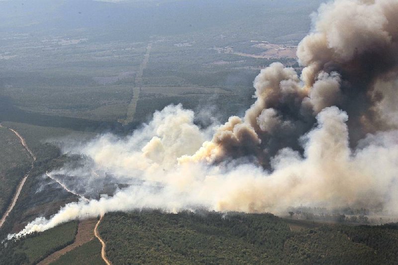 Smoke billows from a wildfire Wednesday near Ola in Yell County. A mandatory evacuation of a rural area between Ola and Birta was under way Wednesday evening, county officials said. 